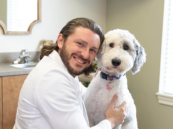 Dentist smiling and hugging a dog