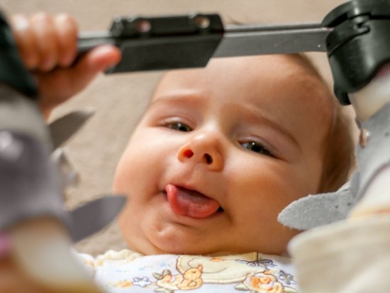 Infant lying down and sticking out its tongue