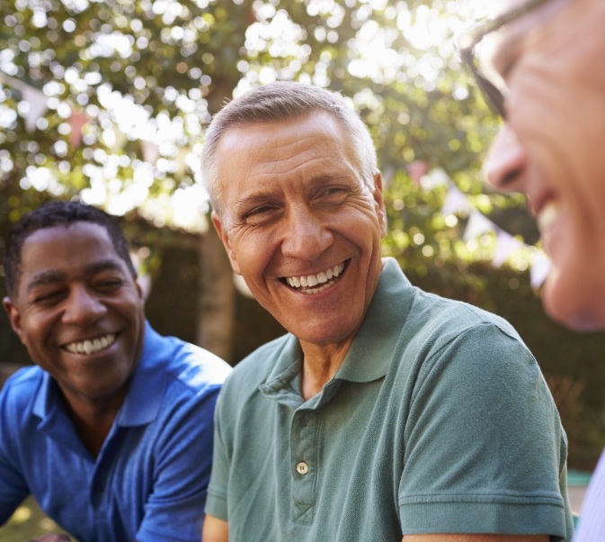 Three men sitting in row and smiling