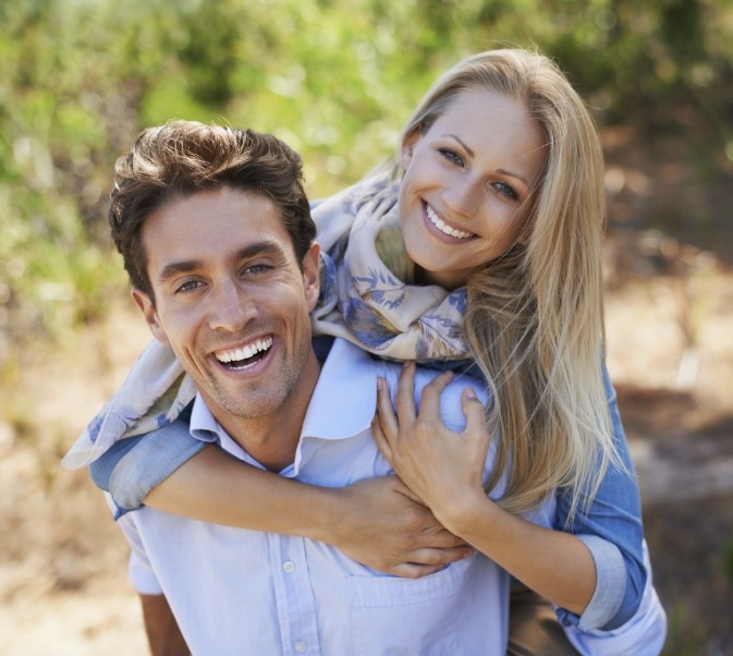 Man giving woman piggyback ride outside after visiting cosmetic dentist in El Reno