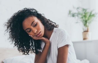 Woman in white shirt with tooth pain sitting on couch