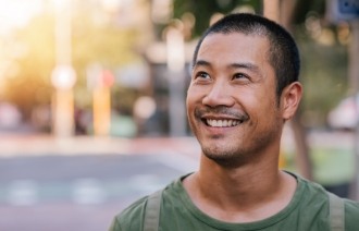 Man in green shirt smiling and walking down street