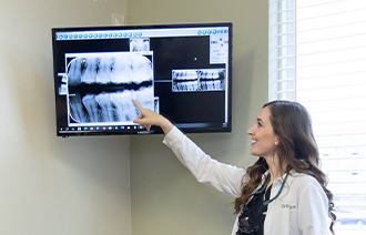 Female dentist pointing to x ray of teeth