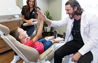 Kid in dental chair high fiving the dentist