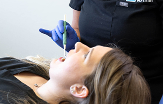 Female dental patient holding mouth open for dentist