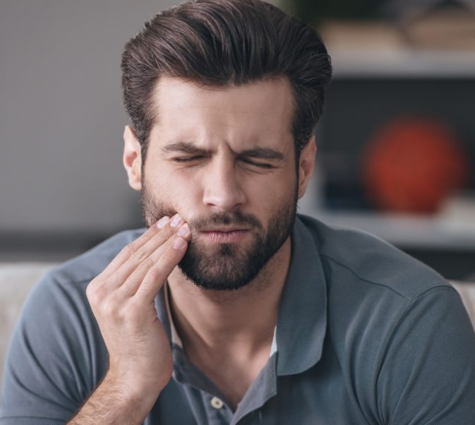 Bearded man with tooth pain rubbing his jaw