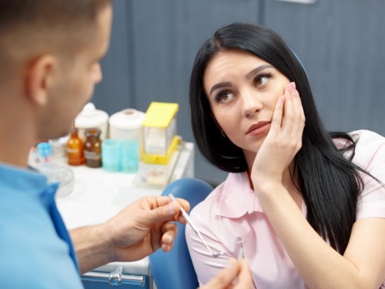 Female dental patient with tooth pain visiting emergency dentist in El Reno