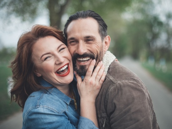 Man and woman standing outside and smiling