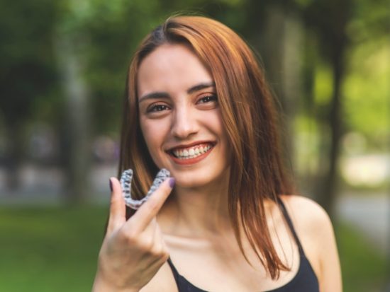 Woman holding an Invisalign clear aligner