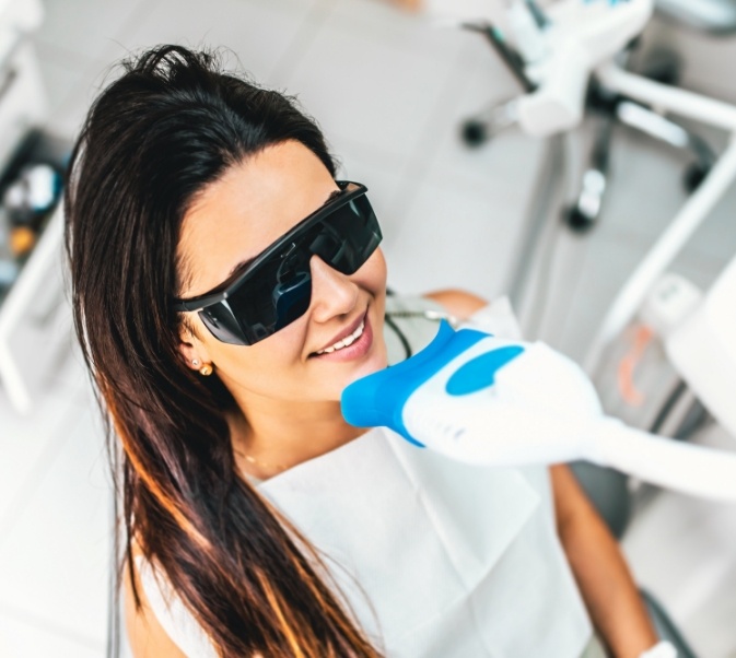 Woman with sunglasses sitting in front of device for teeth whitening in El Reno