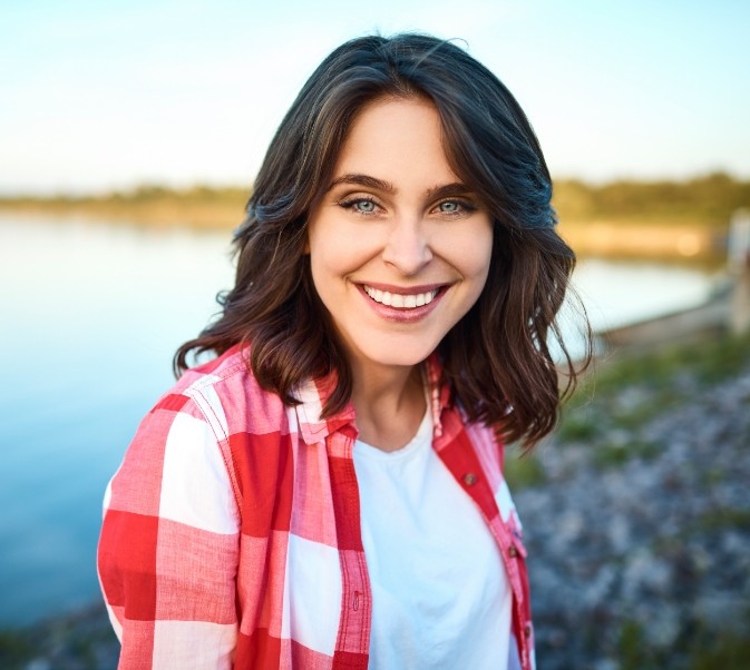 Woman standing by a lake and smiling