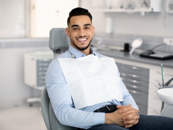 Male dental patient sitting in chair with hands folded